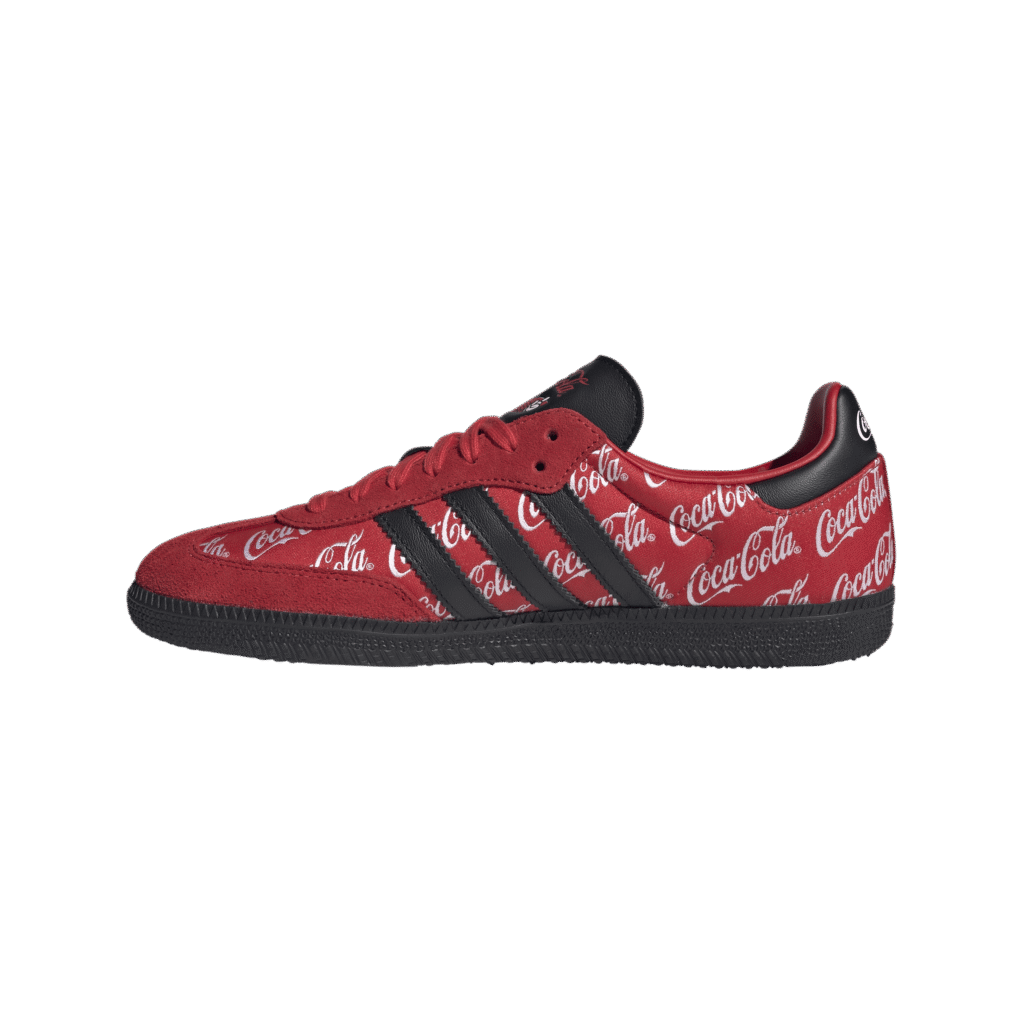 Red sneaker covered in white Coca-Cola script with black stripes along the side on a black background.