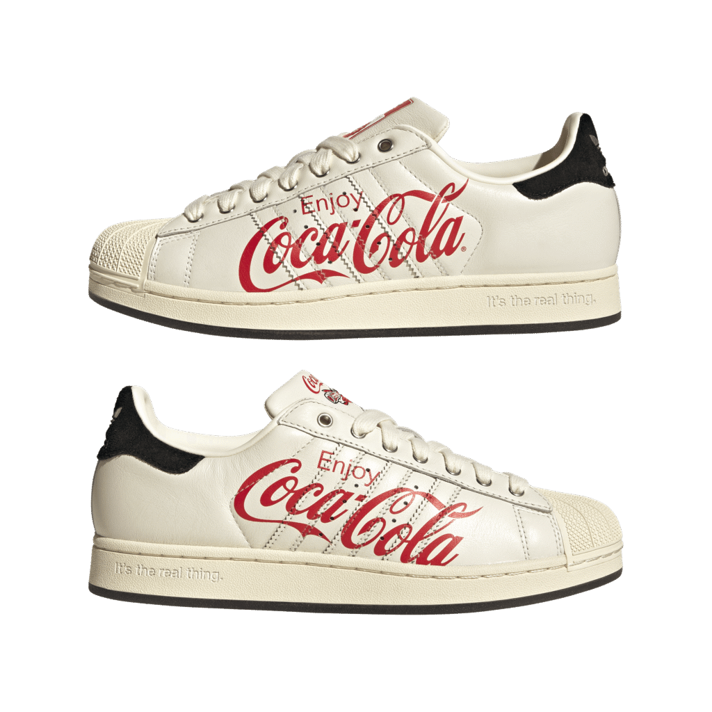 White sneaker with Coca-Cola red script logo along the side and a beige sole and black heel patch in back edges.